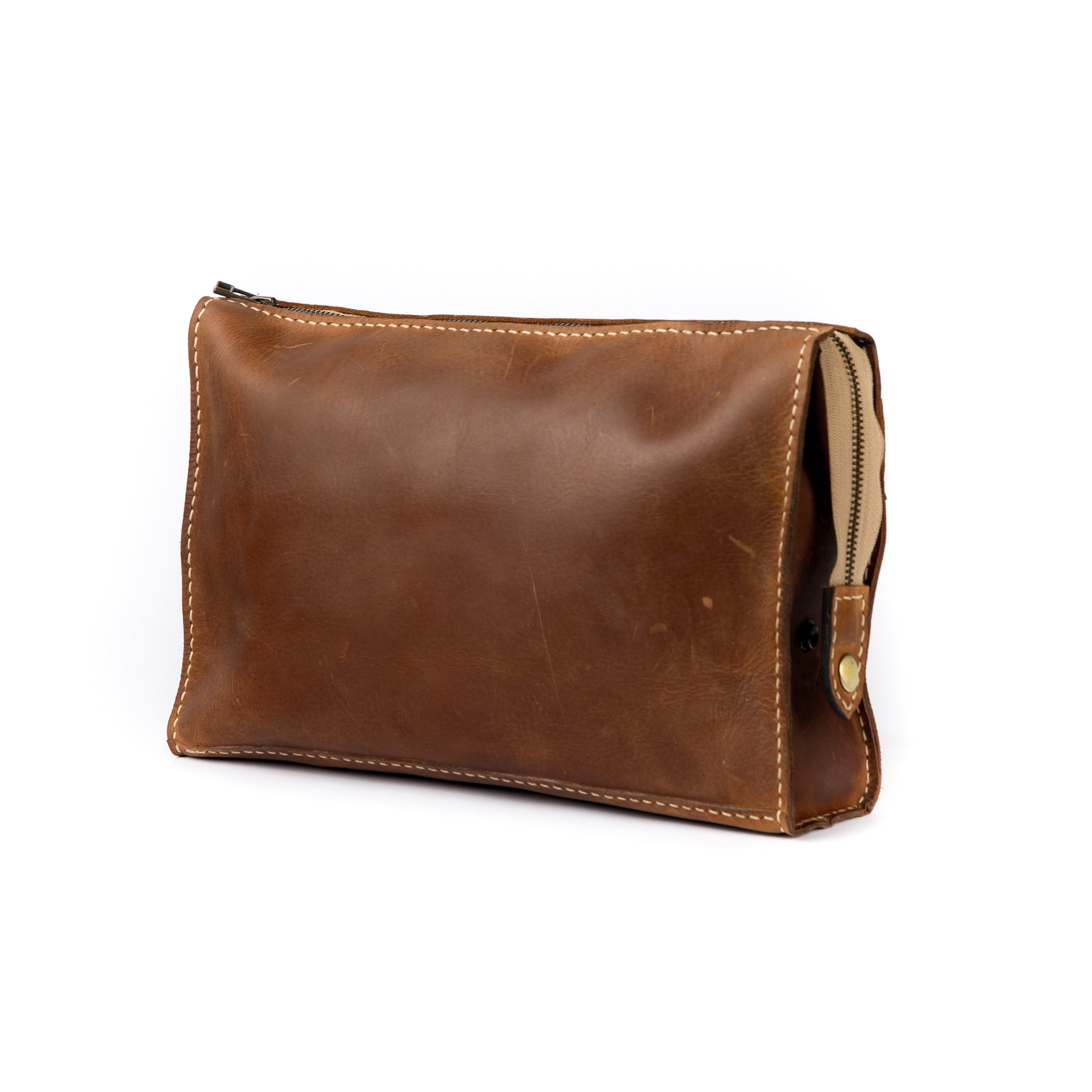 Handmade brown full-grain leather clutch with white stitching and a brass-toned zipper.
