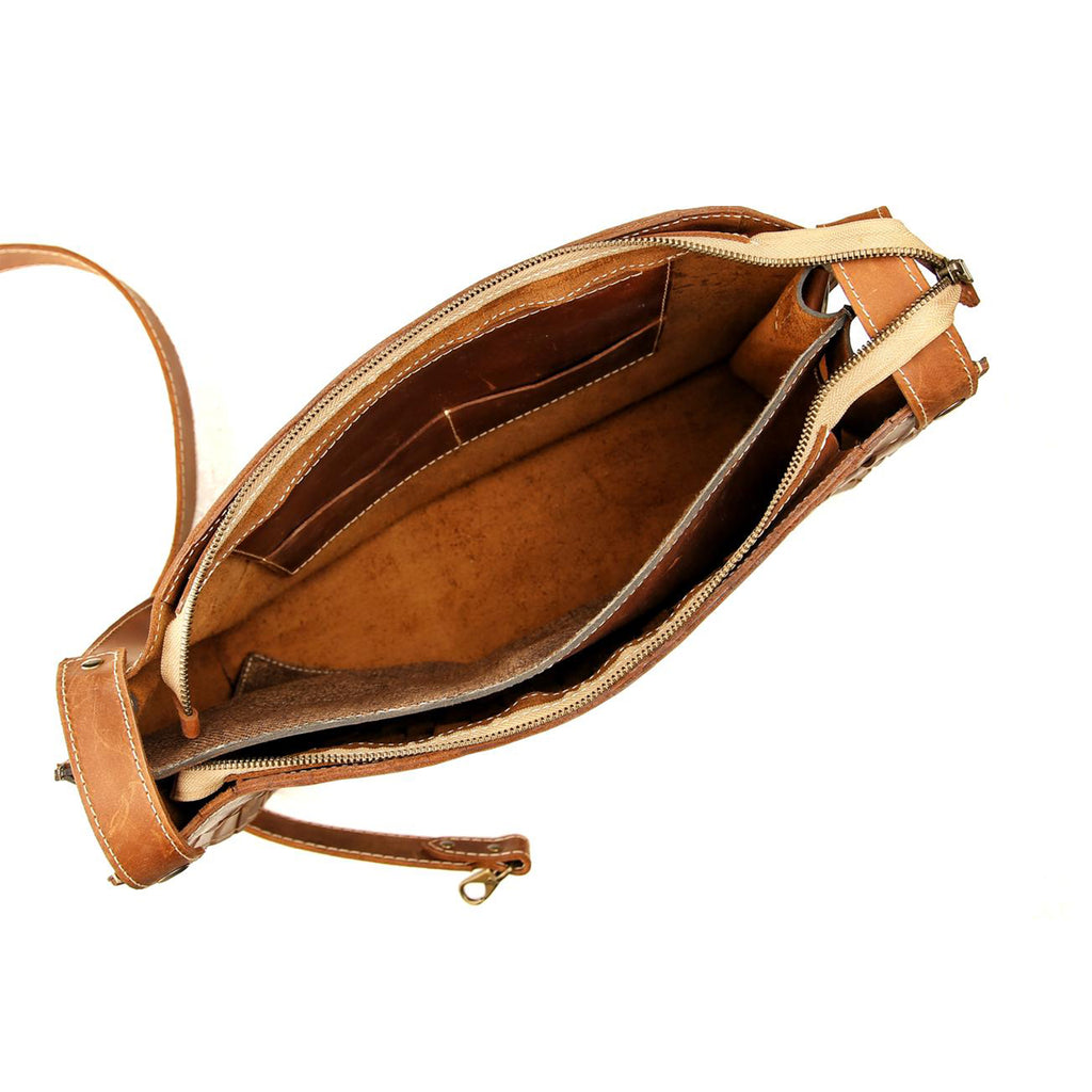 Top-down view of the empty interior of the tan leather 'Grand Braided Pack', clearly showing the multiple internal pockets, leather lining, and spacious compartments designed for efficient daily organization.