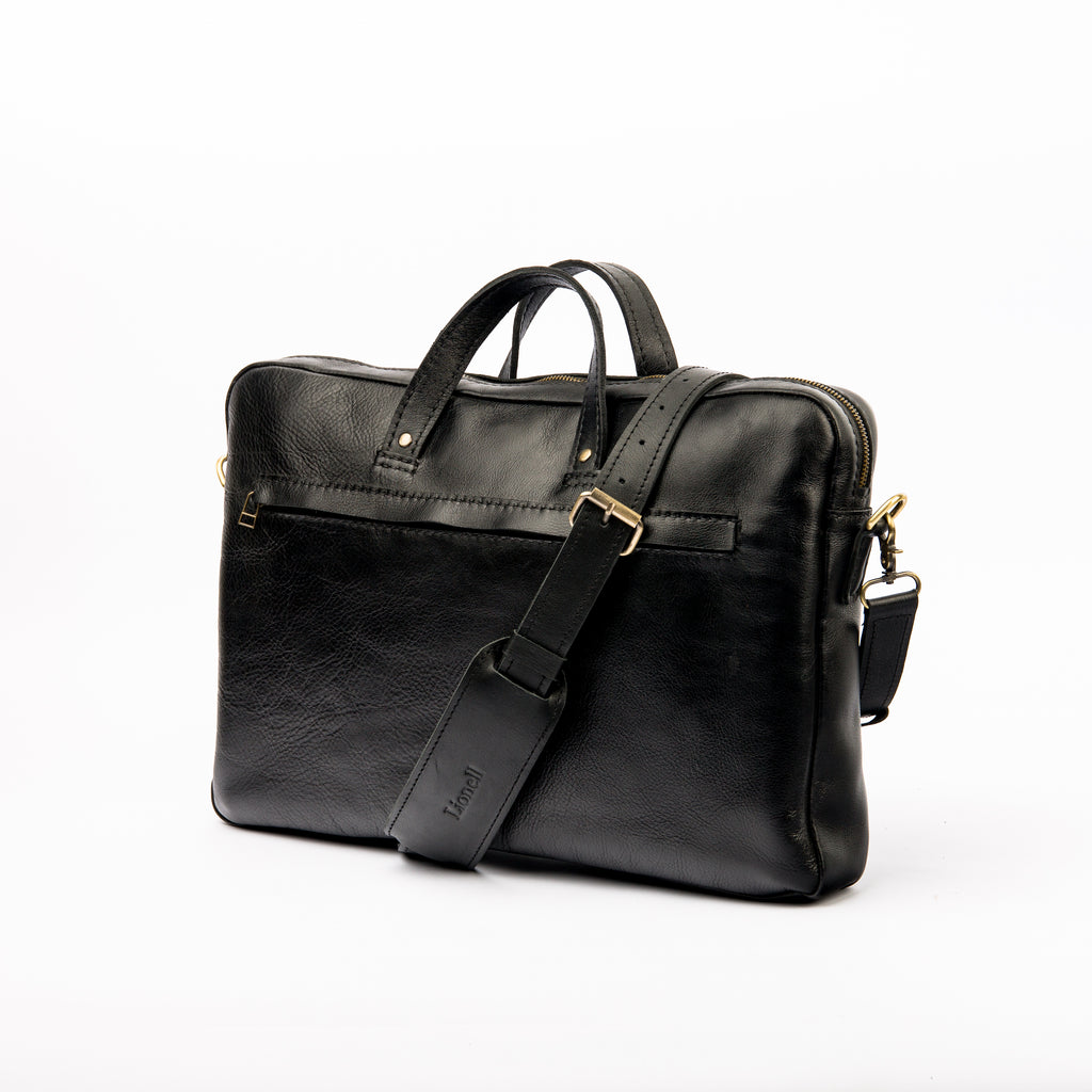 Front view of 'The Noir' pebbled leather laptop bag by LIONELL. Handcrafted from premium black textured leather, featuring a front zippered pocket, sturdy top handles, and a comfortable shoulder strap with a branded shoulder pad, displayed on a clean white background.
