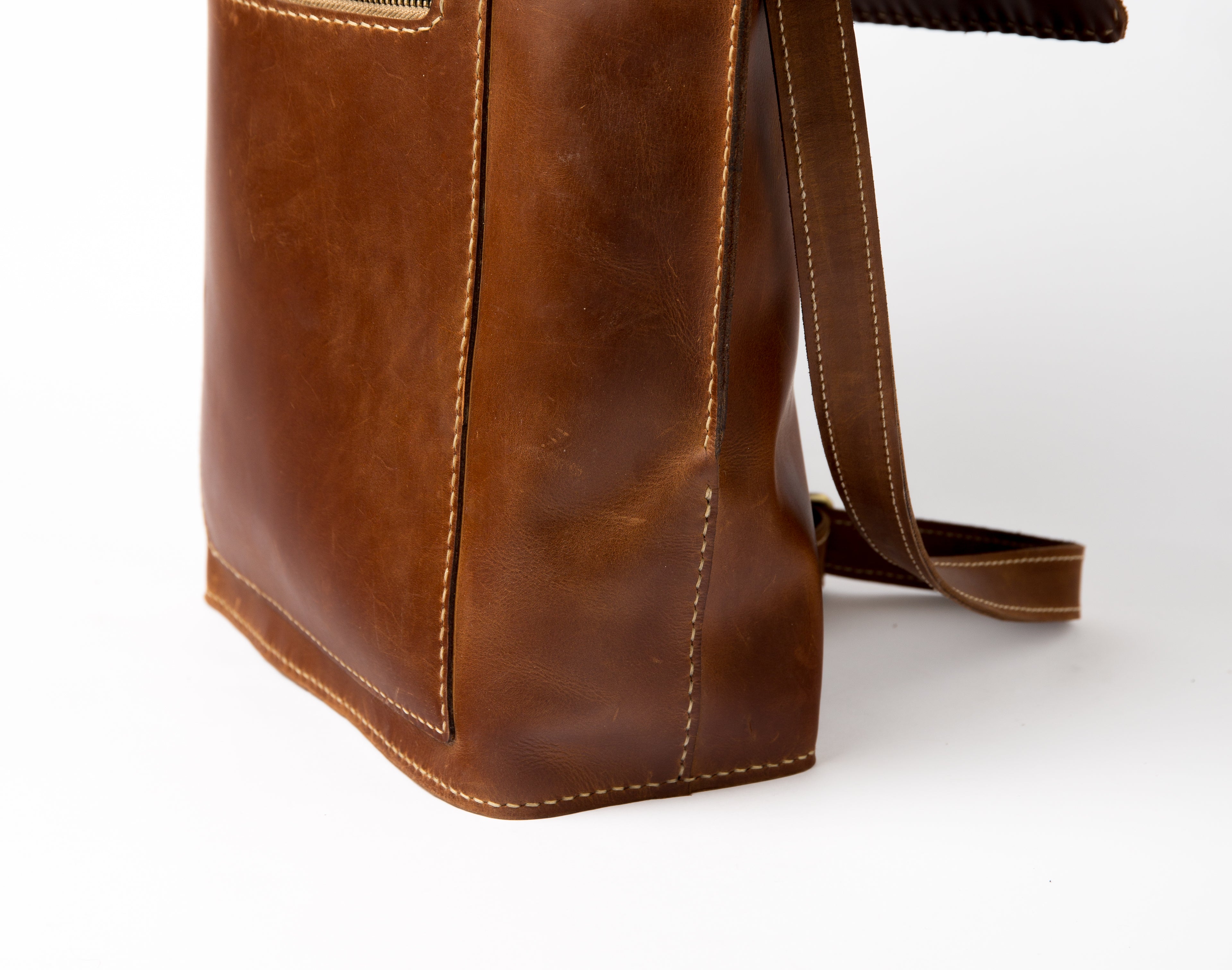 Side profile of "The Sphinx" leather bag showing durable handmade stitching and reinforced bottom corner.