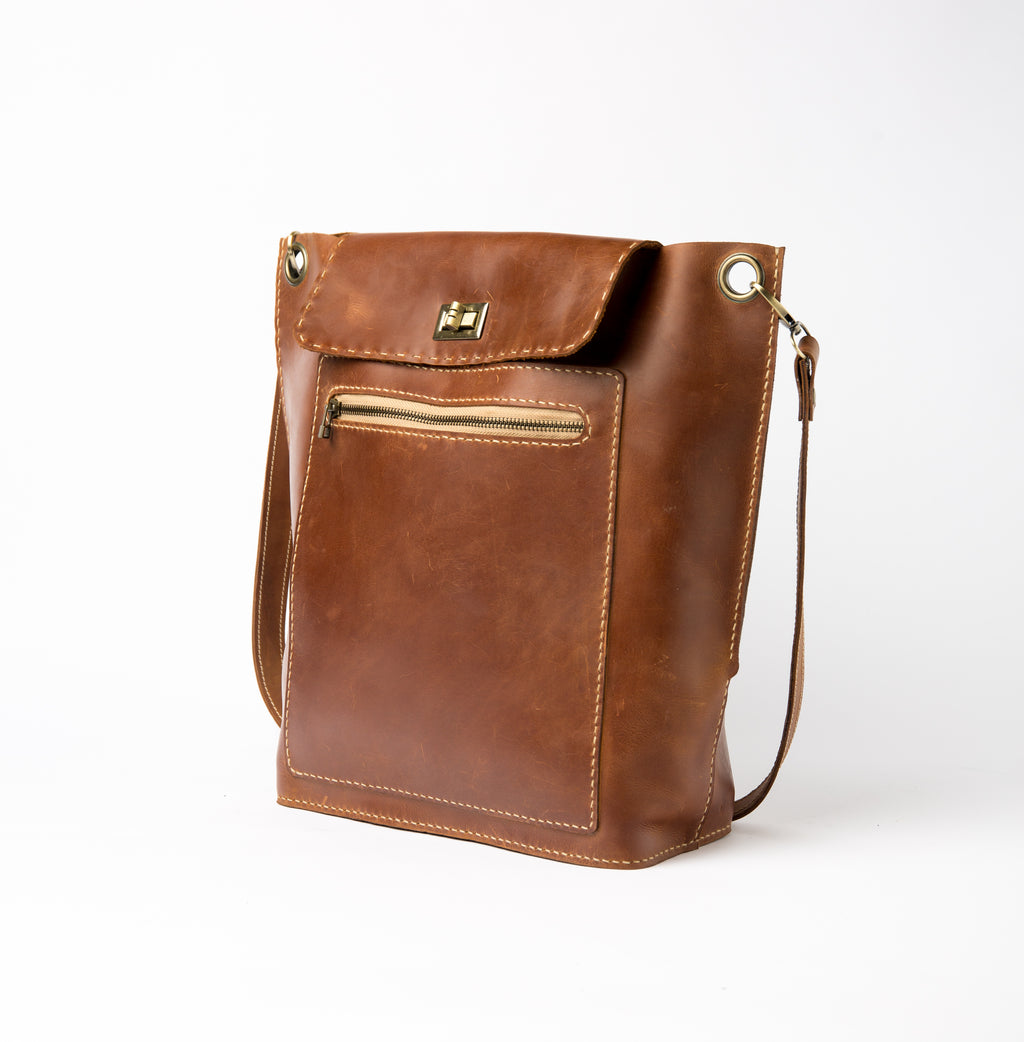 Front of Lionell "The Sphinx" handmade leather crossbody bag with front zipper pocket and brass turn lock.