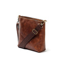 A side-view photo of 'The Urban Crossbag' by LIONELL; handcrafted from rich brown genuine leather, featuring a modern slim design with visible stitching and an adjustable dark brown fabric shoulder strap, displayed on a clean white background.