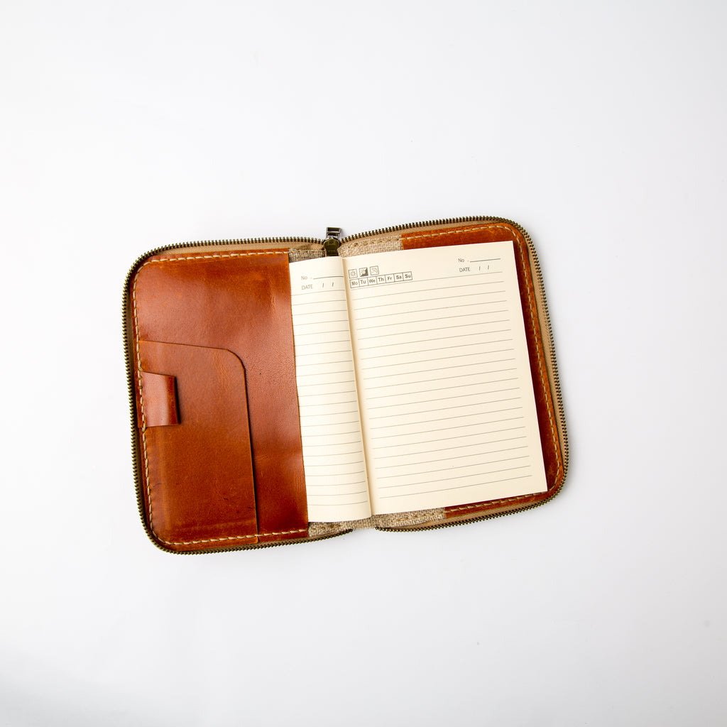 Open view of Lionell zip-around refillable notebook cover showing interior card slots, pen loop, and paper.